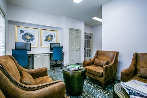 a living room with couches and chairs and a desk with a computer